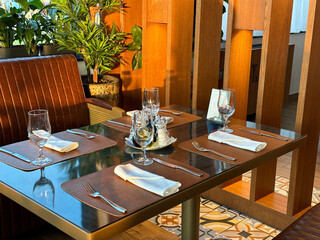 Cozy restaurant interior with elegantly set table, ready for guests. the warmth of the wooden accents and green plants create a welcoming atmosphere.