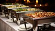 © Iona - Chafing dishes filled with a variety of delicious foods at a catering event, ready to serve guests and enhance the celebration.