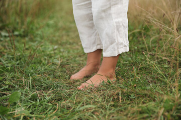 Canvas Print - Little child standing barefoot on green grass outdoors, closeup. Enjoying nature