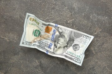 One crumpled dollar banknote on grey table, top view