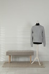 Canvas Print - Female mannequin with sweater and bench near light wall