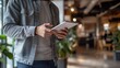 © Lion - close up person standing in a modern office space, dressed in smart casual attire, holding a digital tablet with an attentive posture