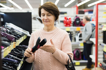 Portrait of a European woman choosing an electric styler near the shelves with goods in an electronics and household ..appliances store