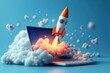 © Myimages - Rocket coming out of laptop screen, blue background.