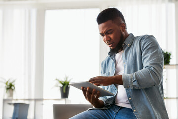 Poster - Concerned african american employee browsing data on digital tablet, can not find necessary information before presentation.