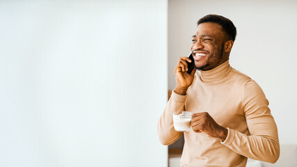 Aufkleber - Always In Touch. Smiling Black Man Having Phone Conversation Drinking Coffee Standing Near Window Indoor. Copy Space