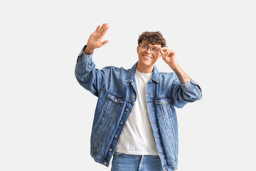 Poster - Young man in stylish eyeglasses waving hand on light background