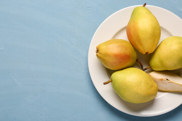 Plate with fresh pears on blue background