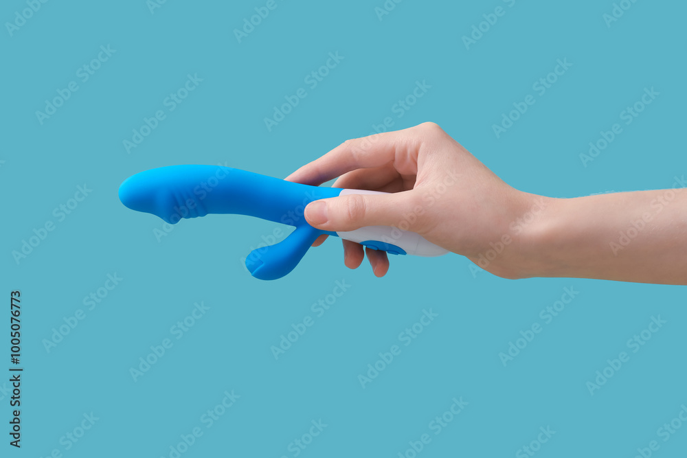 Female hand with vibrator on blue background