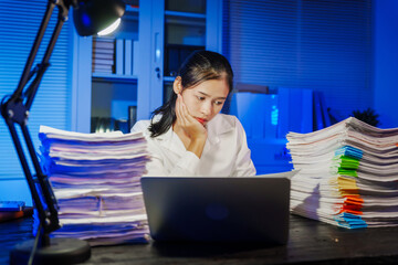 confident Asian businesswoman works late into the night, surrounded by a stack of papers in a busy office. Overtime leads to office syndrome symptoms like neck pain, headaches, and chronic stress.