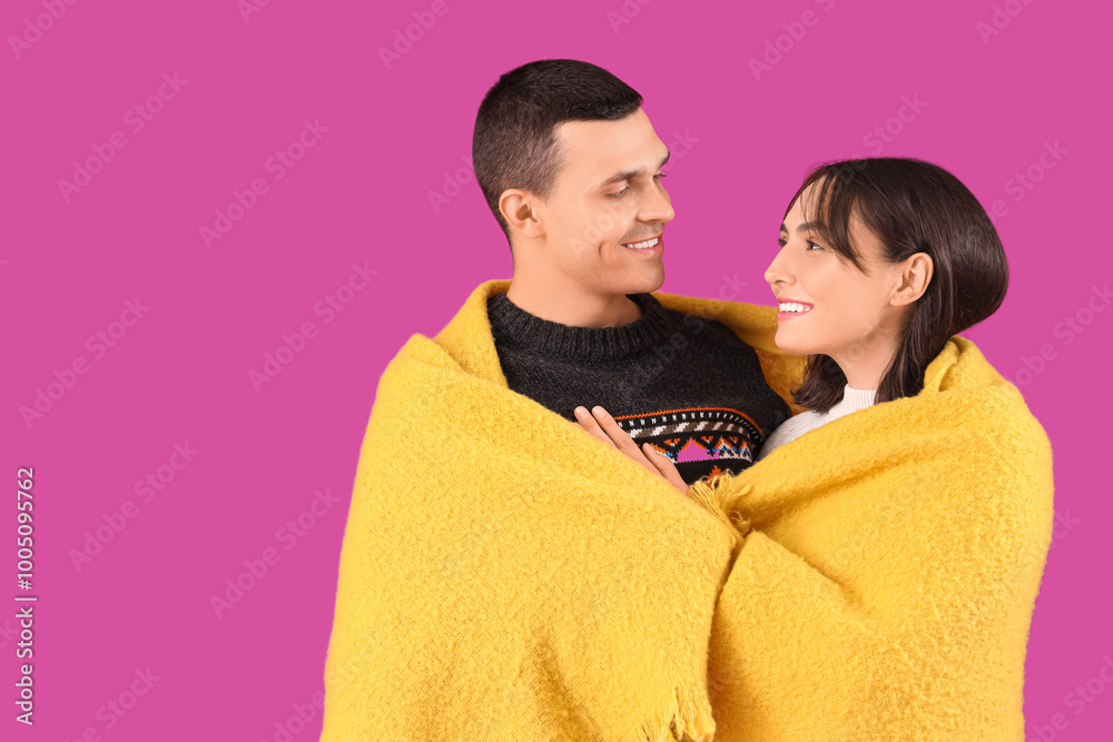Happy young couple with plaid on purple background
