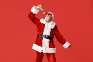 Wall Mural - Santa Claus in sunglasses with microphone singing on red background