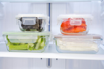 Glass boxes with vegetables in refrigerator front view, concept food storage.