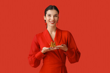 Poster - Beautiful young happy woman with golden dragon figurine on red background. Chinese New Year celebration