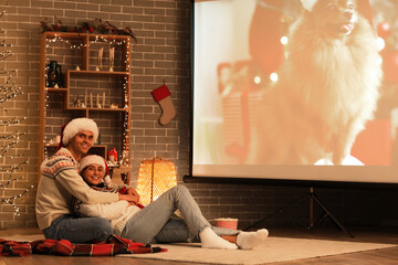 Canvas Print - Young couple watching Christmas movie on projector screen at home