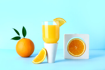 Decorative podium with glass of fresh orange juice on blue background