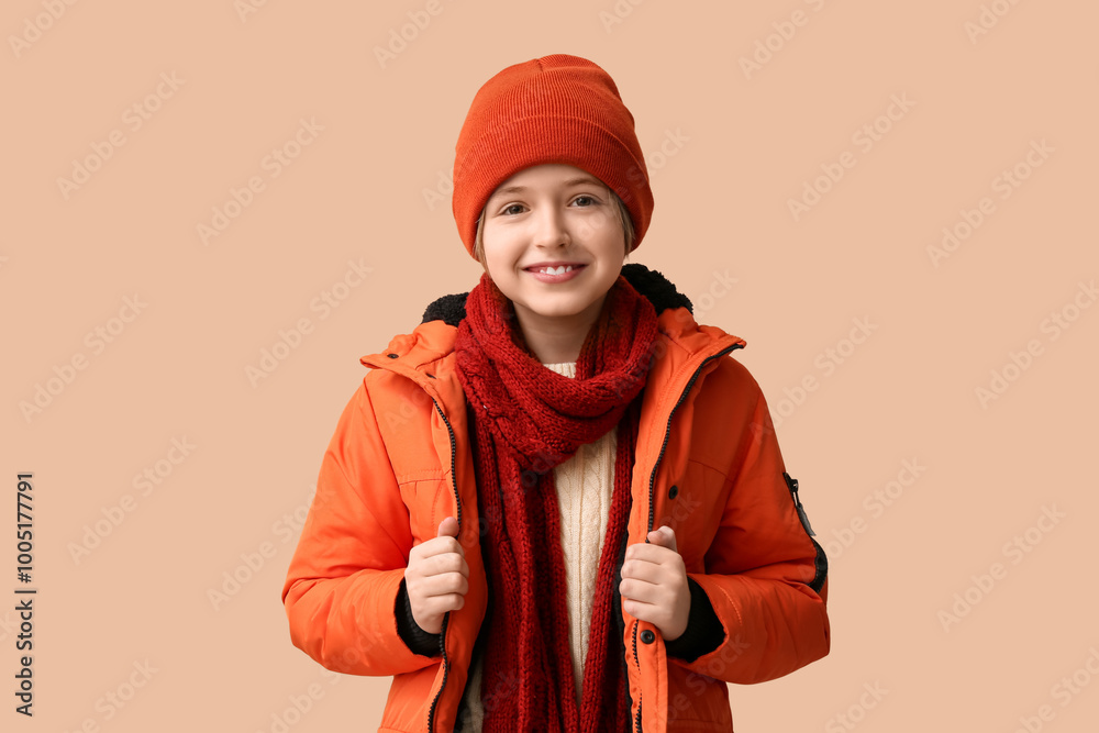 Cute little happy boy in winter clothes on beige background