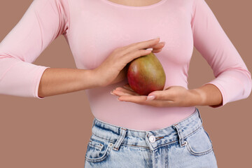 Poster - Young Asian woman with fresh mango on brown background