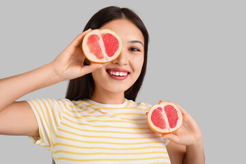 Wall Mural - Beautiful young Asian woman with fresh grapefruit on grey background