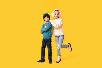 Poster - Cute little happy children in warm winter clothes on yellow background