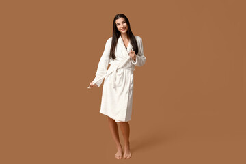 Sticker - Beautiful young happy woman in bathrobe after shower on brown background