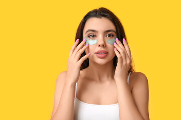 Poster - Beautiful young woman with under-eye patches on yellow background