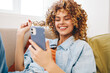 © SHOTPRIME STUDIO - Happy Woman Holding Mobile Phone on Sofa in Cozy Living Room