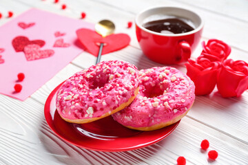 Plate with donuts and decor on white wooden background. Valentine's Day celebration