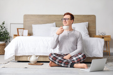 Sticker - Morning of handsome young happy man in stylish pajamas drinking tea at home