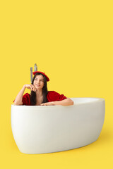 Sticker - Beautiful woman with beret in bathtub on yellow background