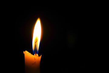 fire on white candle isolated on darkness with advertising empty space.