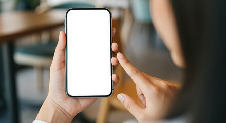 Woman hand holding a smartphone with a blank white screen on a blurred cafe background.