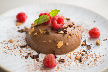 Wall Mural - Dark chocolate flan with almonds. Decorated with cocoa powder and raspberries.