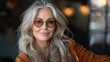 © nataliya_ua - Elegant woman with gray hair and sunglasses enjoying a  cozy café atmosphere on a sunny afternoon. Generative AI