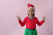 © Phimwilai - Adorable Asian little girl with a Christmas hat The party shows various action poses, standing, smiling, dancing, and having fun in various poses, on a pink background. Holiday concept, festival.