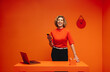 © Jacob Lund - Businesswoman in vibrant, monochromatic orange workspace holding a smartphone and laughing