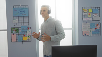 Young man doing handsfree call in modern office with brainstorming ideas on whiteboard in background