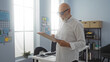 © Krakenimages.com - Mature man with grey hair and beard examines clipboard in modern workplace with sunlight streaming through office windows
