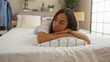 © Krakenimages.com - Young, beautiful, brunette, hispanic, woman lying on bed indoors in a cozy, modern bedroom setting.