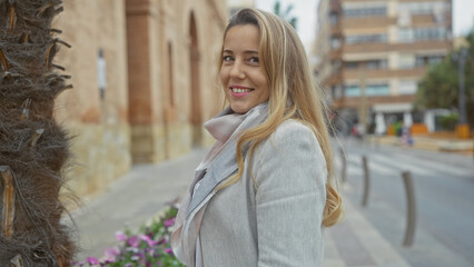 Smiling young caucasian woman outdoors on a city street posing fashionably, encapsulating beauty and urban lifestyle.