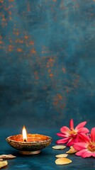 Wall Mural - A candle is lit in a small bowl on a blue background. The candle is surrounded by pink flowers, which add a touch of color and elegance to the scene