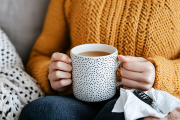 Woman in a warm mustard colored sweater holding a mug of tea