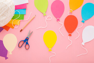 Wall Mural - Colorful balloon shapes, scissors, pencil and string yarn on light pink table background. Pastel color. Making and creating festive decoration from application paper. Closeup. Top down view.