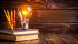 © ARVD73 - Image of light bulb is lit up next to a stack of books and a pencil holder on the wooden table. International day of education. copy space.