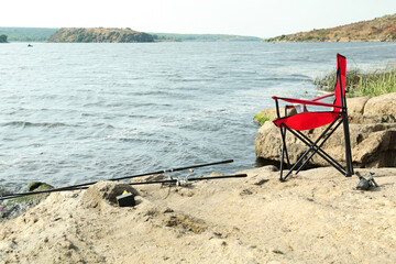 Sticker - Chair and two fishing rods on shore near lake outdoors