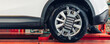 © kanpisut - Car wheel centering machine adjustment. Auto service mechanic installing wheel alignment sensor on tire during vehicle suspension alignment adjustment