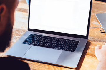 Fototapete - cropped view of male using laptop computer with mock up screen while sitting at wooden desktop table