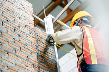 An engineer holding a tape measure inspects the building construction standards.