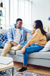 © BullRun - African American couple in love sitting on sofa together talking to each other during leisure time in living room, young  dark skinned marriage having conversation about their relations on sofa