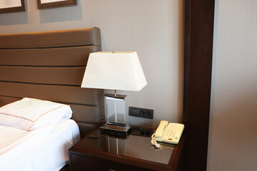 Wall Mural - Stylish lamp and telephone with handset on bedside table in hotel room